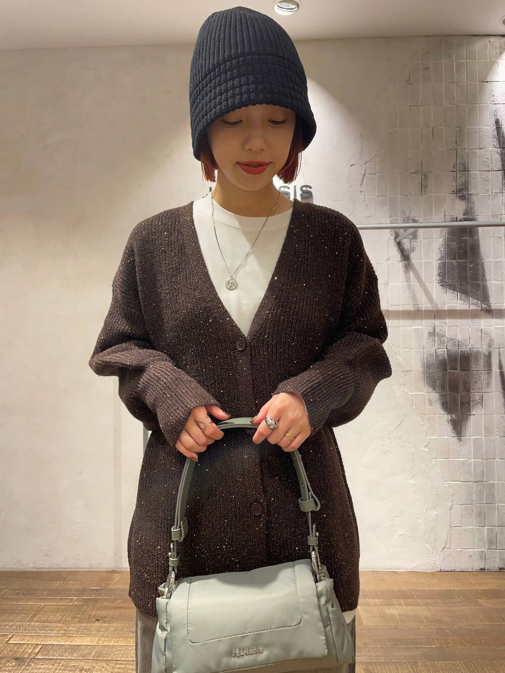 ブラック系のデニムパンツ、グリーン系のショルダーバッグ、ブラック系のブーツを着用したレディースの冬コーディネートの2枚目の写真