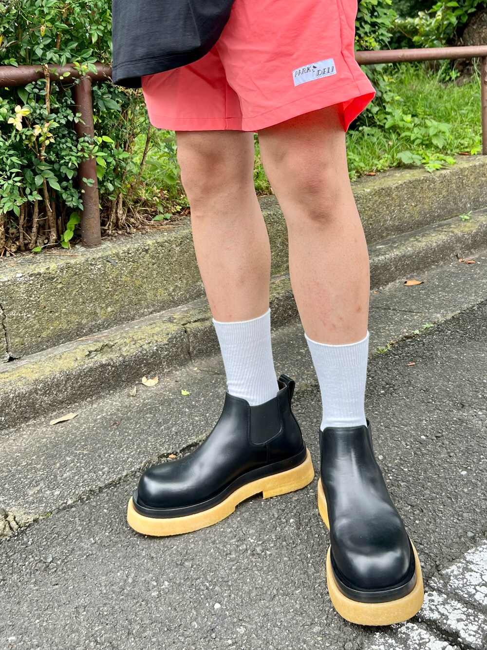 ブラック系のTシャツ/カットソー、ピンク系のパンツ、ブラック系のブーツを着用したメンズの夏コーディネートの4枚目の写真