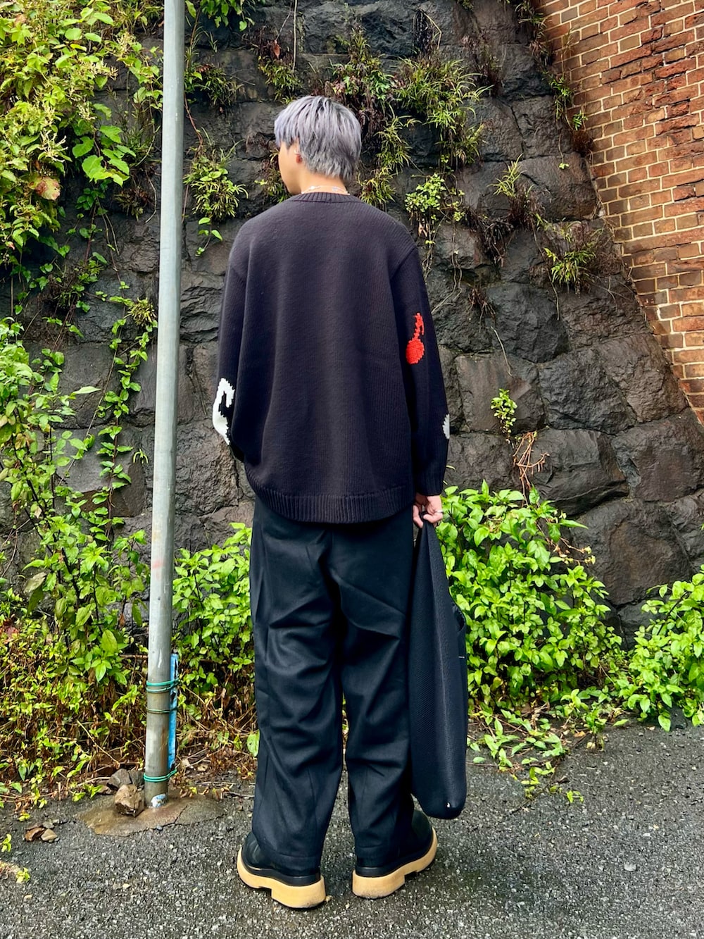 ブラック系のスラックス、ブラック系のブーツ、ブラック系のハンドバッグを着用したメンズの秋コーディネートの2枚目の写真