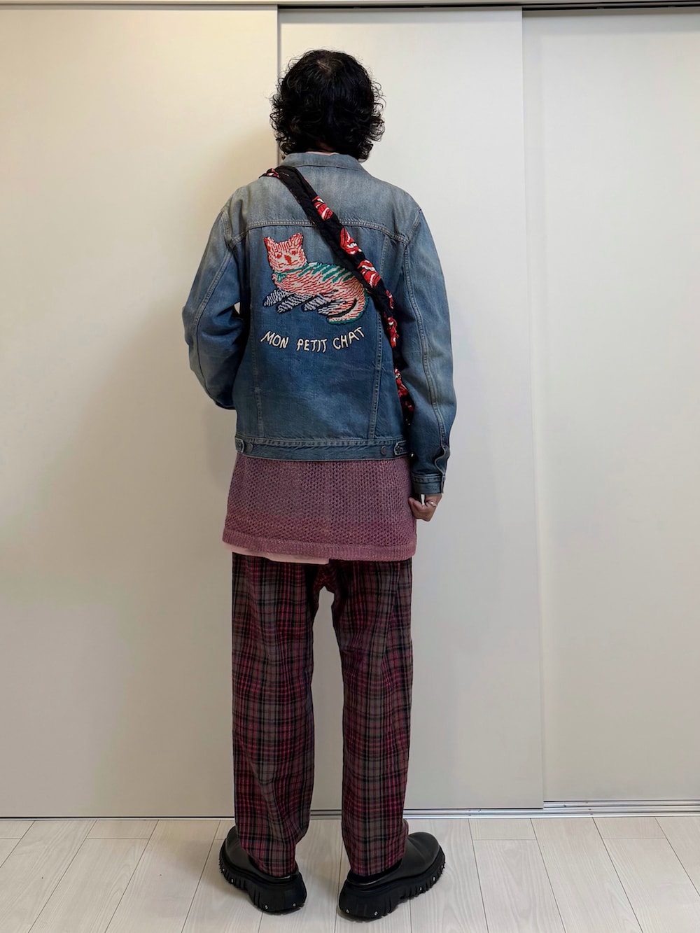 レッド系のパンツ、ブラック系のドレスシューズ、ブルー系のデニムジャケットを着用したメンズの春コーディネートの3枚目の写真