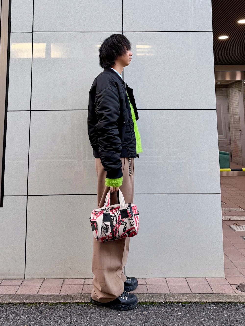 ベージュ系のスラックス、ブラック系のシューズ、ブラック系のMA-1を着用したメンズの秋コーディネートの2枚目の写真