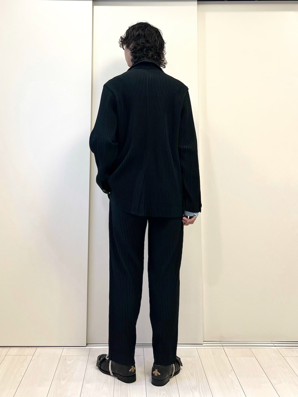 ブラック系のテーラードジャケット、ブラック系のパンツ、ブラック系のパンプスを着用したメンズの冬コーディネートの3枚目の写真