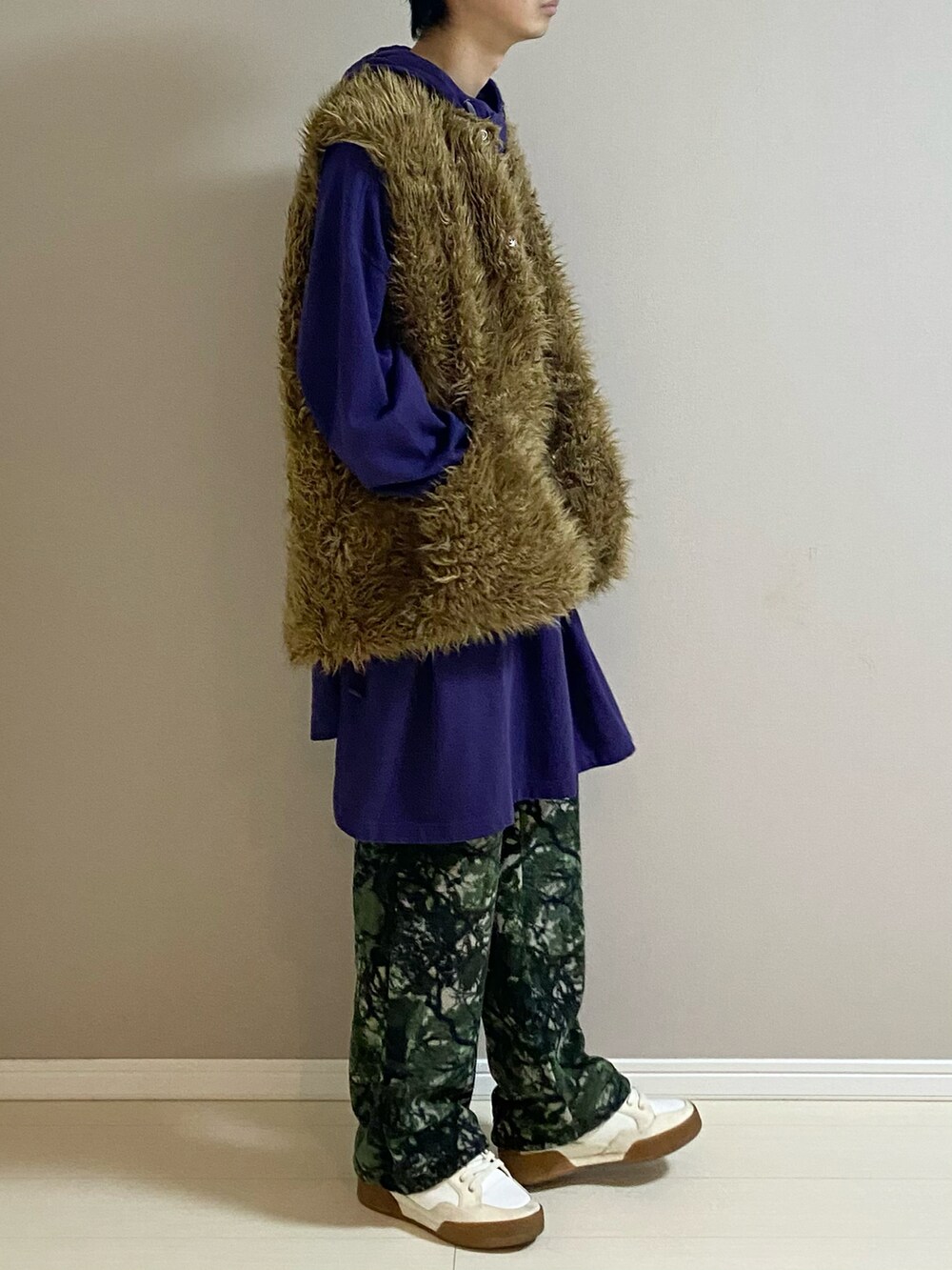 ホワイト系のスニーカー、ブラウン系のベスト、パープル系のTシャツ/カットソーを着用したメンズの冬コーディネートの2枚目の写真