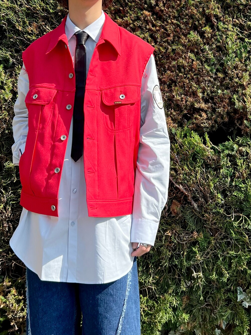 ブラック系のドレスシューズ、ブルー系のデニムパンツ、レッド系のブルゾンを着用したメンズの春コーディネートの4枚目の写真