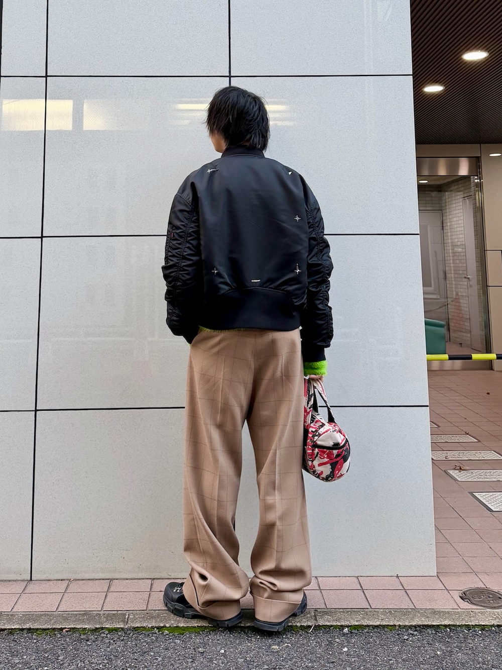 ベージュ系のスラックス、ブラック系のシューズ、ブラック系のMA-1を着用したメンズの秋コーディネートの3枚目の写真