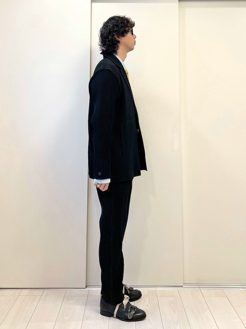 ブラック系のテーラードジャケット、ブラック系のパンツ、ブラック系のパンプスを着用したメンズの冬コーディネートの2枚目の写真