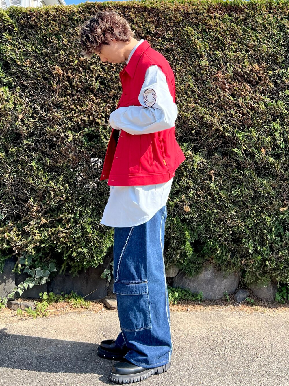 ブラック系のドレスシューズ、ブルー系のデニムパンツ、レッド系のブルゾンを着用したメンズの春コーディネートの2枚目の写真