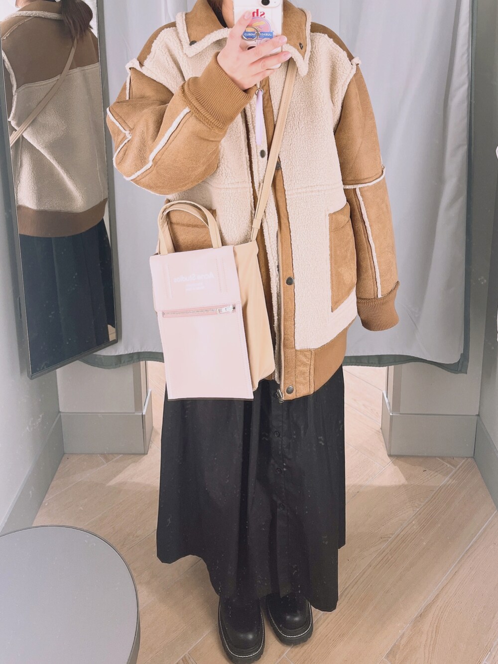 ベージュ系のムートンコート、ピンク系のショルダーバッグ、ブラック系のブーツを着用したレディースの冬コーディネートの2枚目の写真