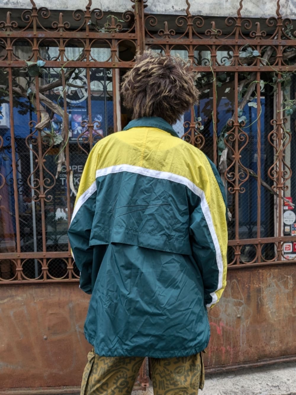 グリーン系のナイロンジャケットを着用したメンズの秋コーディネートの2枚目の写真