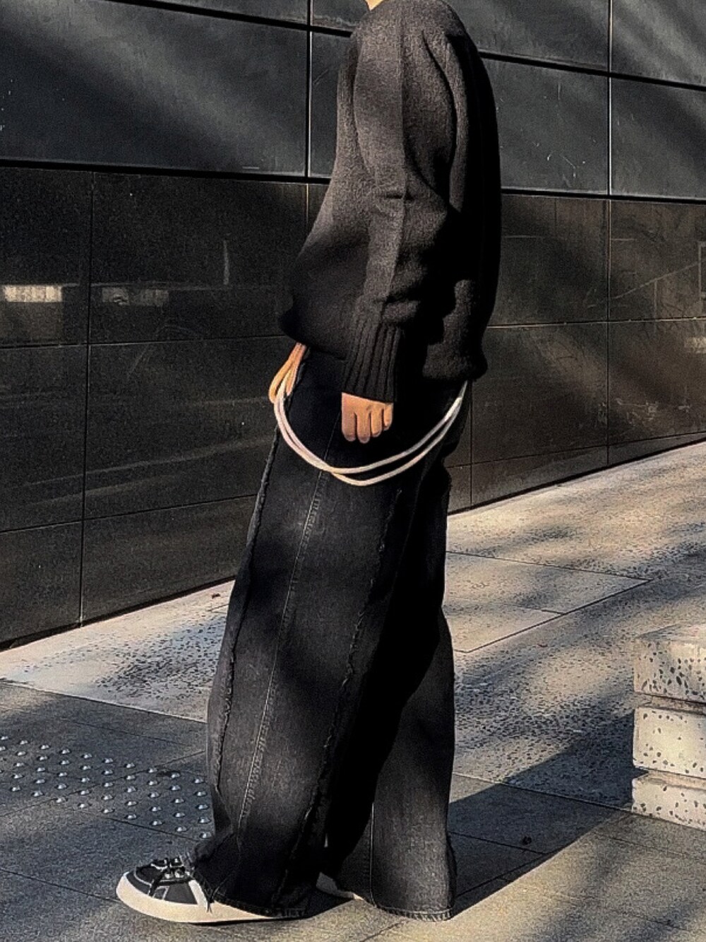 ブラック系のデニムパンツ、ベージュ系のベルト、シルバー系のネックレスを着用したメンズの春コーディネートの2枚目の写真