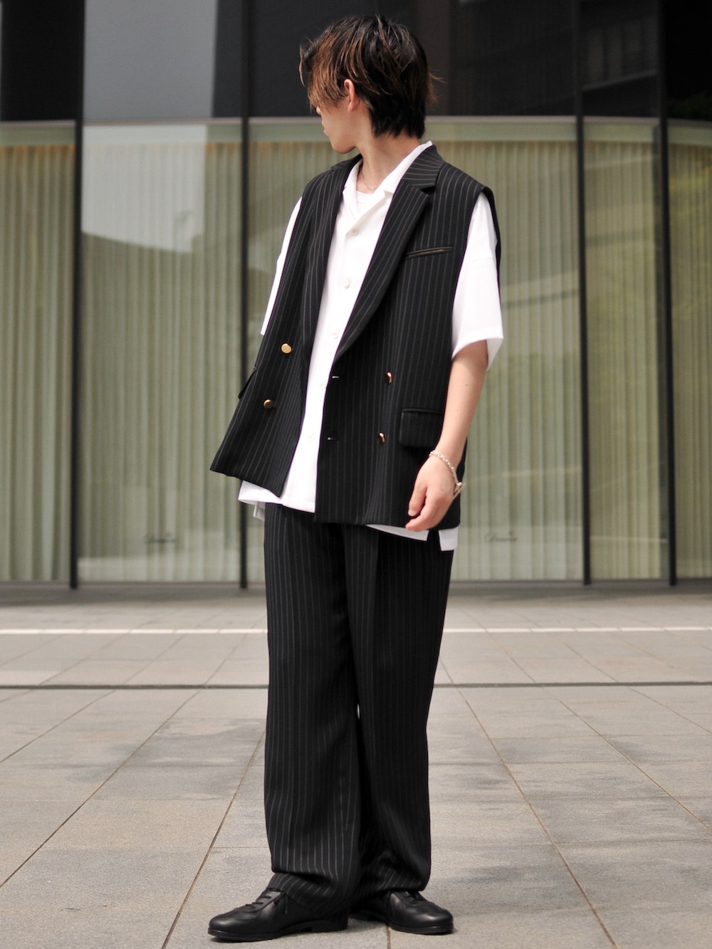 ブラック系のベスト、ホワイト系のシャツ/ブラウス、ブラック系のスラックスを着用したメンズの春コーディネートの2枚目の写真