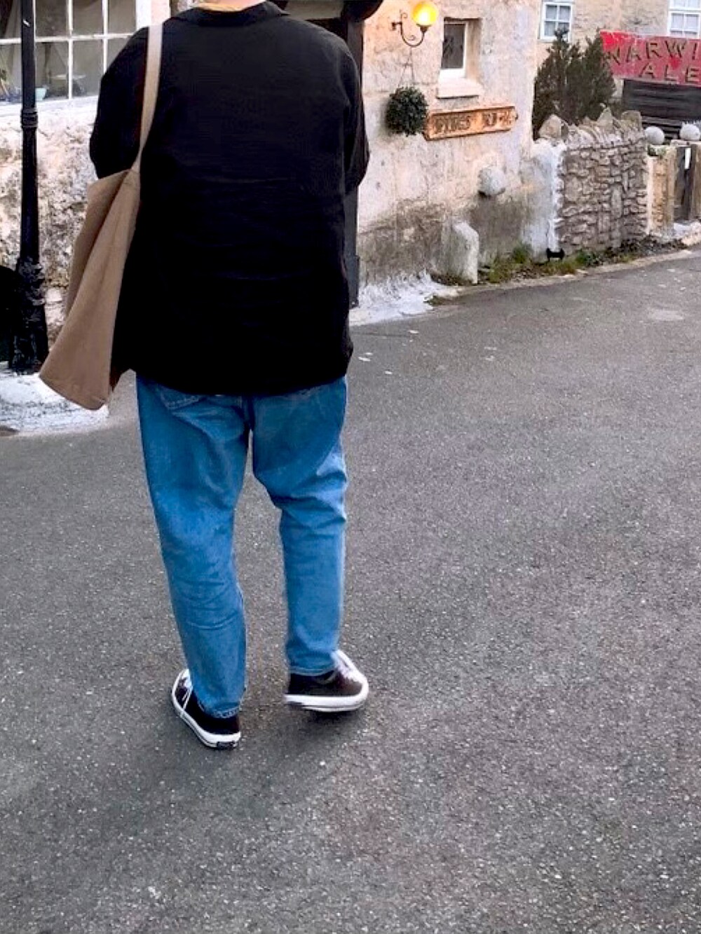 ブルー系のデニムパンツ、ブラック系のスニーカー、ベージュ系のトートバッグを着用したメンズの冬コーディネートの2枚目の写真