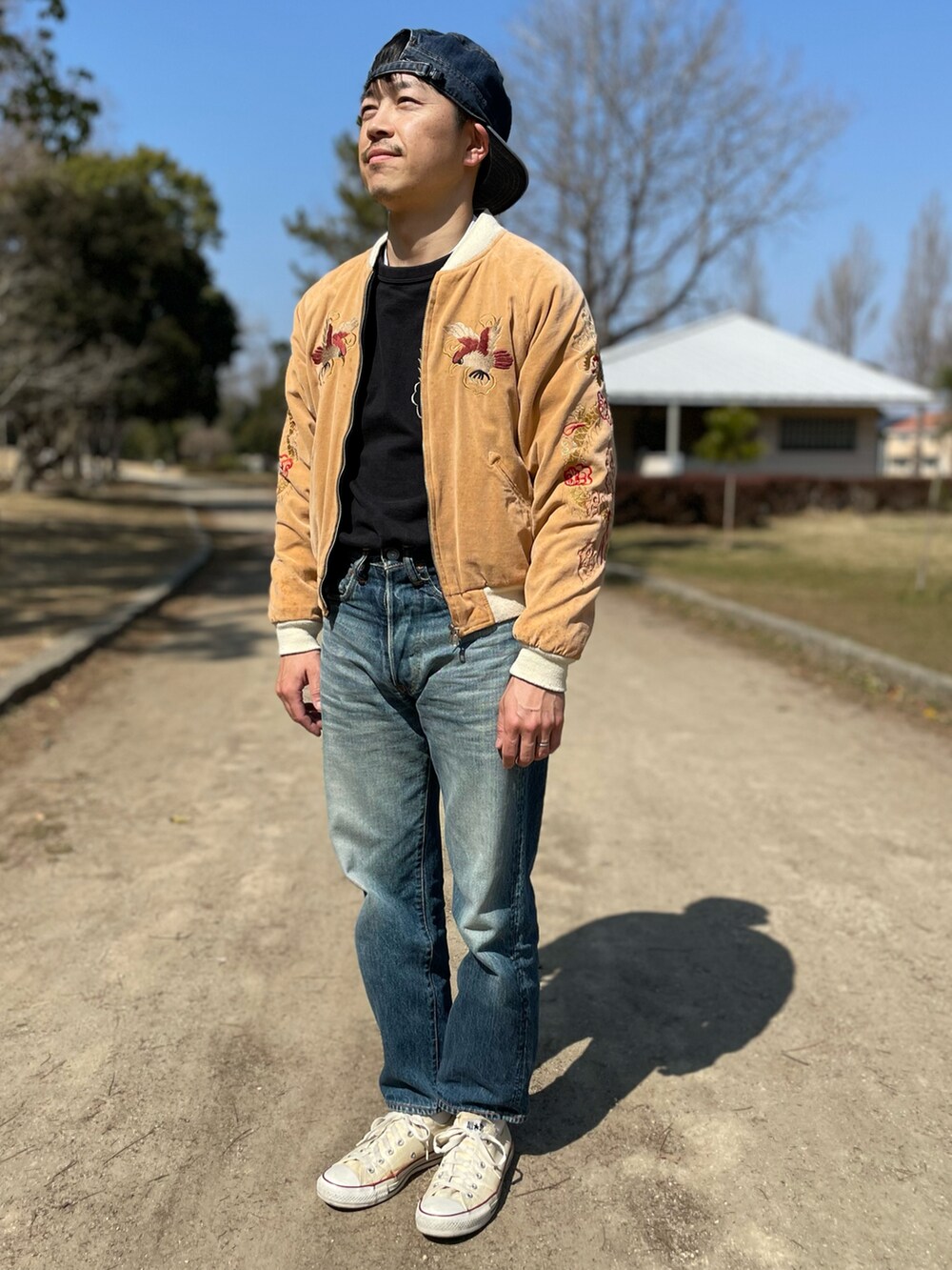 ブルー系のデニムパンツ、ベージュ系のスカジャン、ブラック系のスウェットを着用したメンズの春コーディネートの4枚目の写真