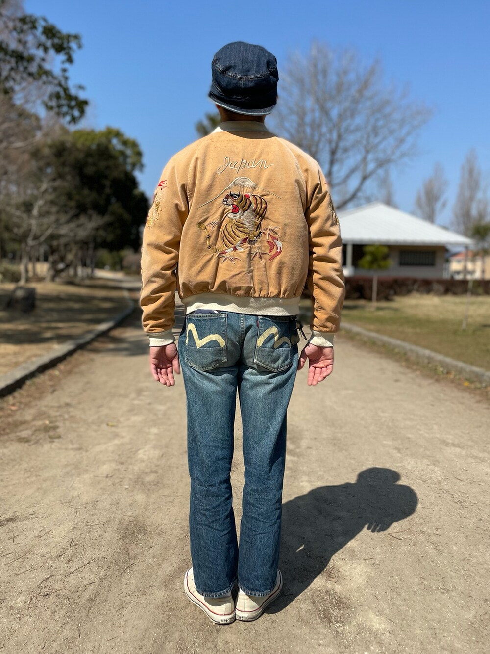 ブルー系のデニムパンツ、ベージュ系のスカジャン、ブラック系のスウェットを着用したメンズの春コーディネートの3枚目の写真