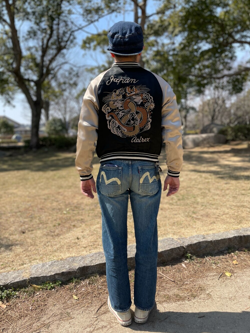 ブルー系のデニムパンツ、ベージュ系のスカジャン、ブラック系のスウェットを着用したメンズの春コーディネートの2枚目の写真