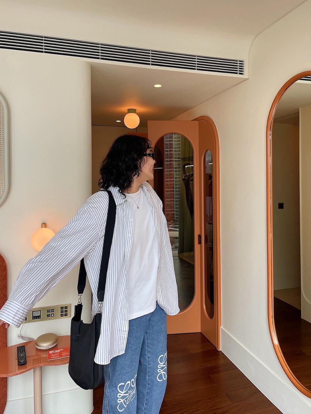 ブラック系のサンダル、ブルー系のデニムパンツ、ブラック系のショルダーバッグを着用したメンズの夏コーディネートの3枚目の写真