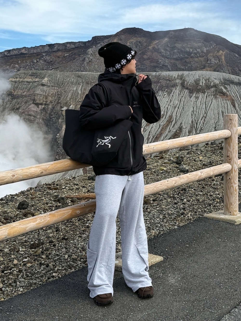 ブラック系のトートバッグ、ブラック系のマウンテンパーカー、ブラウン系のスニーカーを着用したメンズの冬コーディネートの2枚目の写真