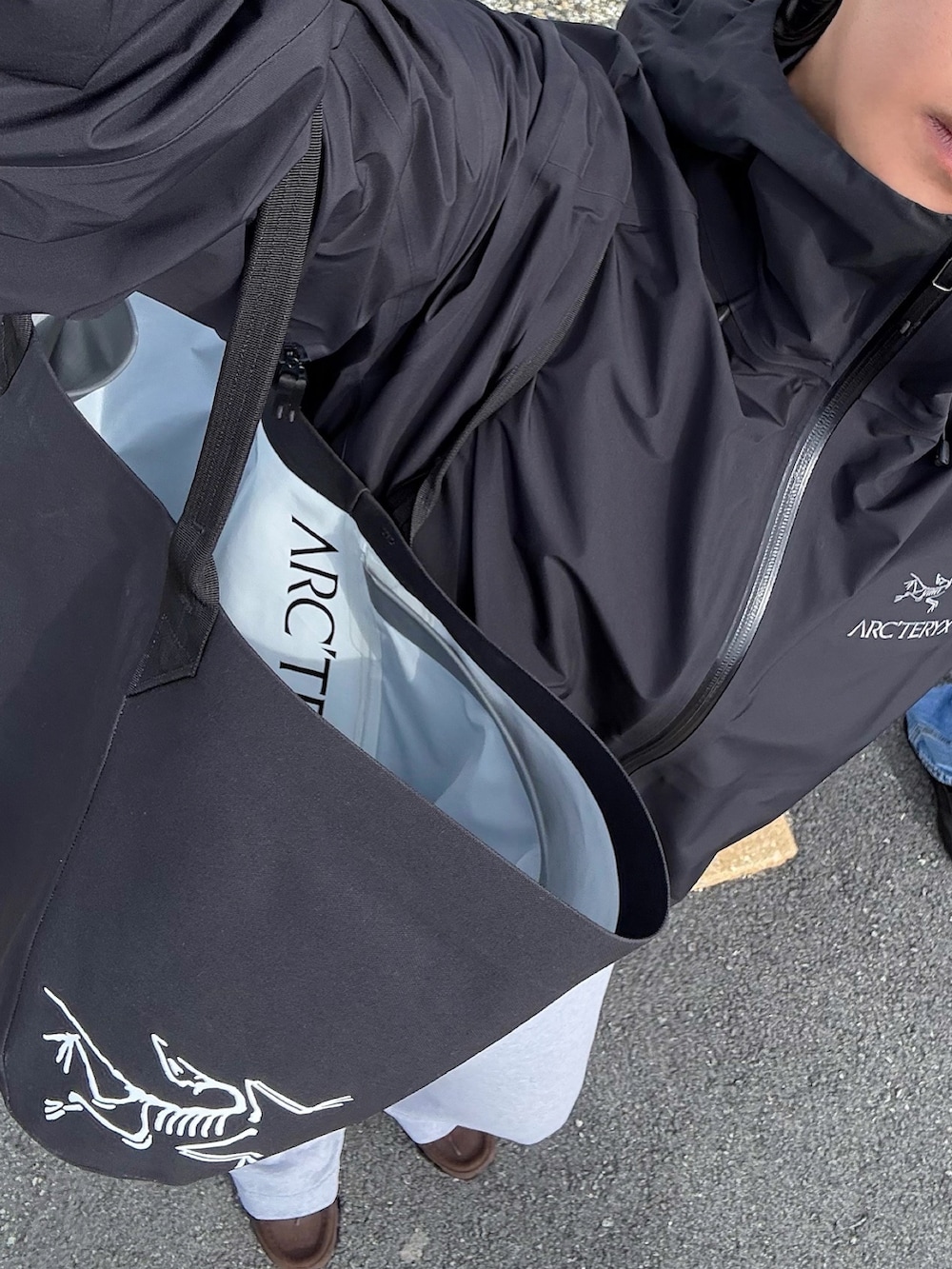 ブラック系のトートバッグ、ブラック系のマウンテンパーカー、ブラウン系のスニーカーを着用したメンズの冬コーディネートの3枚目の写真