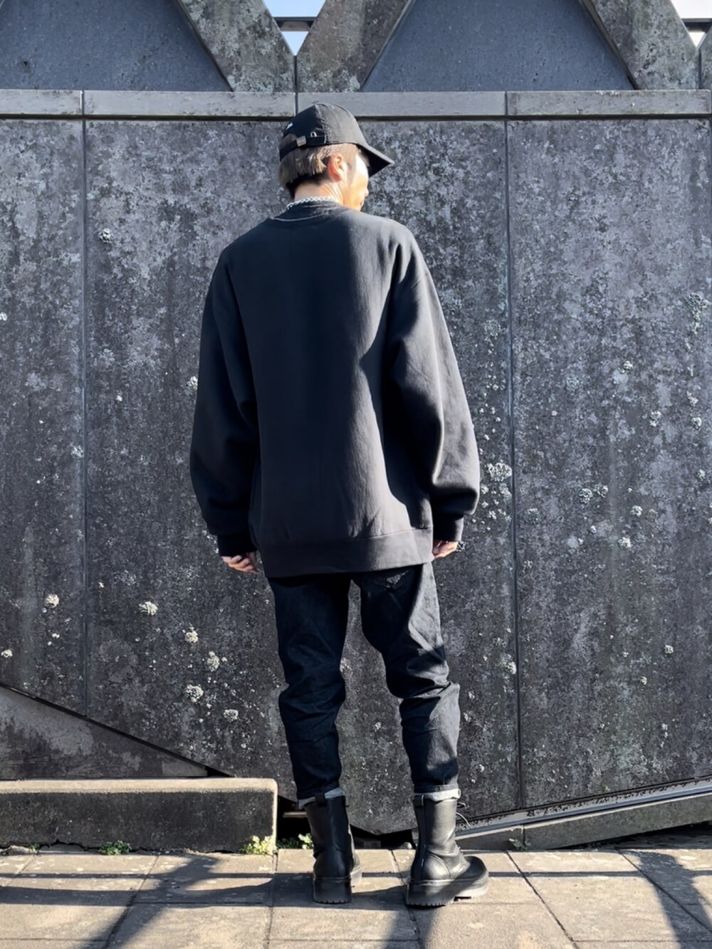ブラック系のデニムパンツ、ブラック系のスウェット、ブラック系のキャップを着用したメンズの秋コーディネートの3枚目の写真