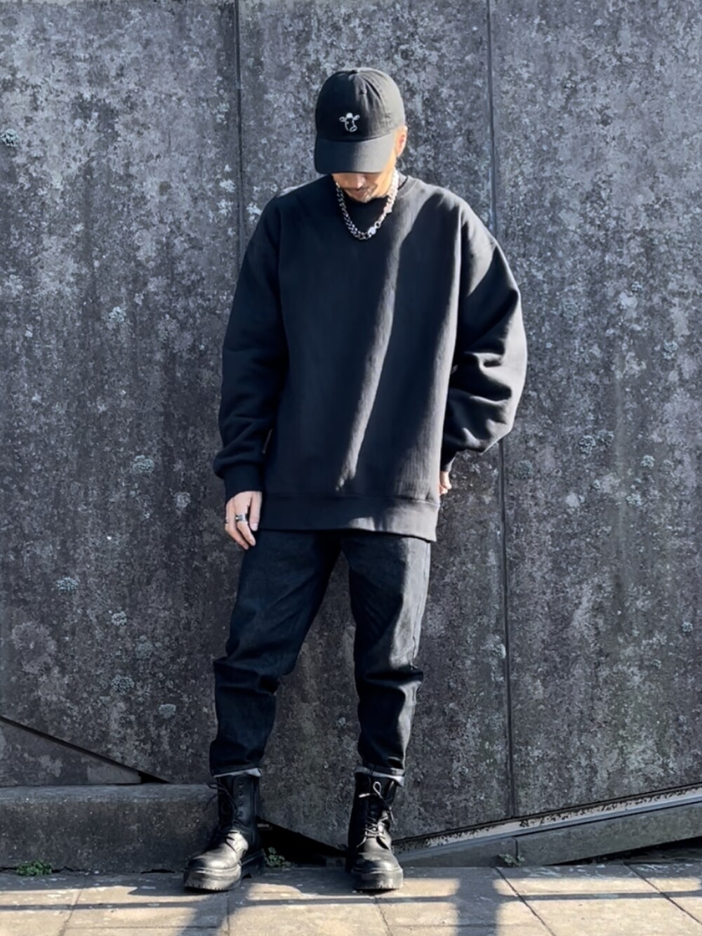 ブラック系のデニムパンツ、ブラック系のスウェット、ブラック系のキャップを着用したメンズの秋コーディネートの2枚目の写真