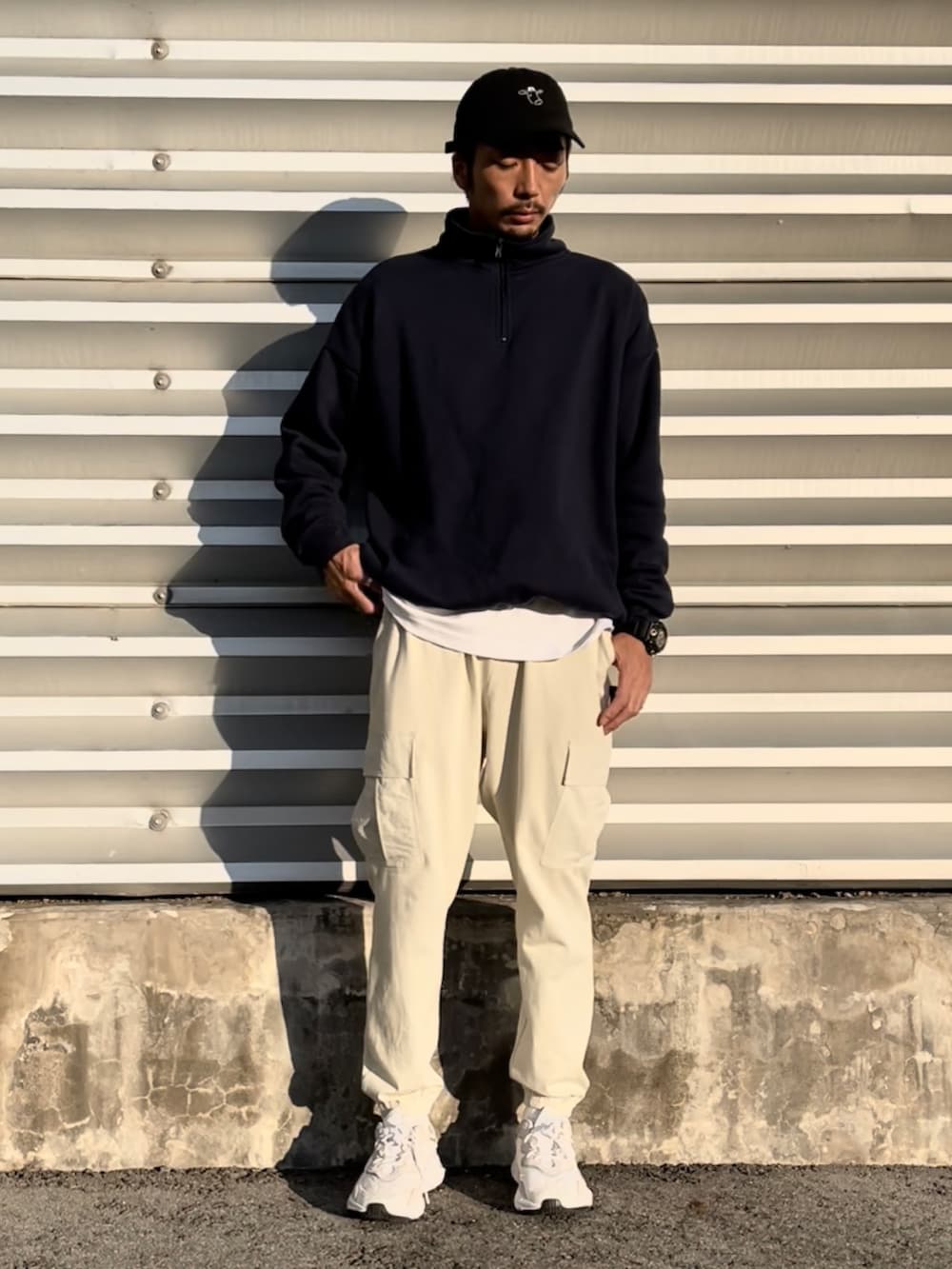ブルー系のトップス、ホワイト系のパンツ、ブラック系の帽子を着用したメンズの秋コーディネートの2枚目の写真