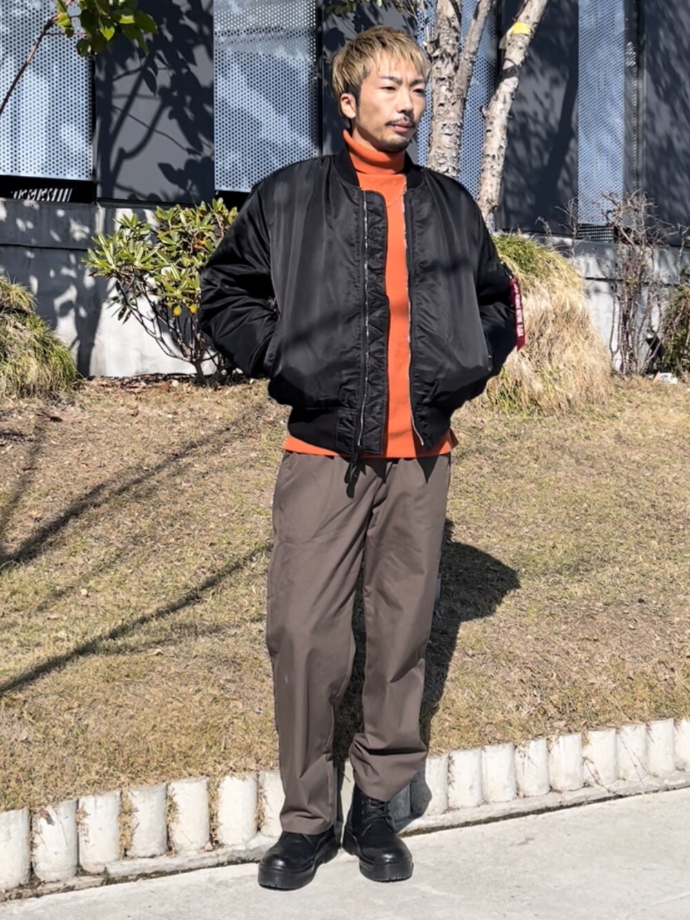 オレンジ系のニット/セーター、ブラウン系のその他パンツを着用したメンズの冬コーディネートの3枚目の写真