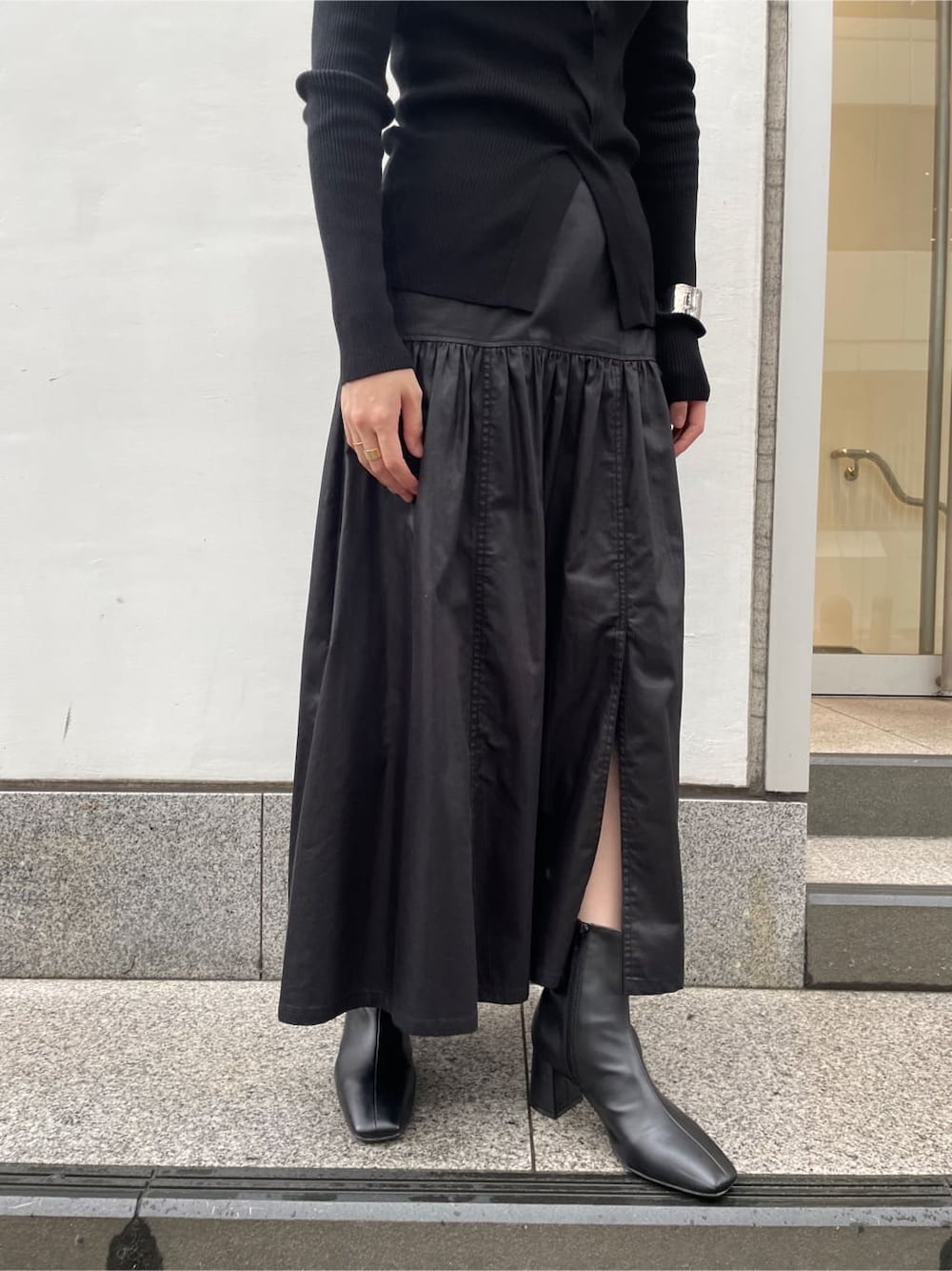 ブラック系のスカート、ブラック系のブーツ、ブラック系のニット/セーターを着用したレディースの夏コーディネートの7枚目の写真