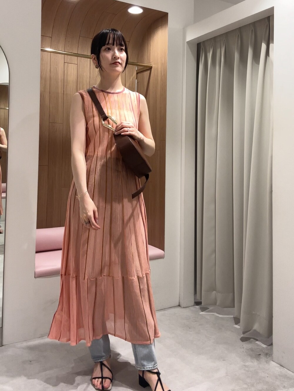 ブラック系のサンダル、ブルー系のデニムパンツ、ブラウン系のショルダーバッグを着用したレディースの夏コーディネートの2枚目の写真