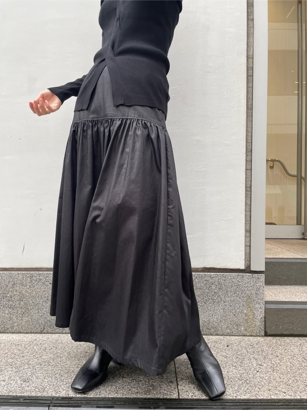 ブラック系のスカート、ブラック系のブーツ、ブラック系のニット/セーターを着用したレディースの夏コーディネートの6枚目の写真
