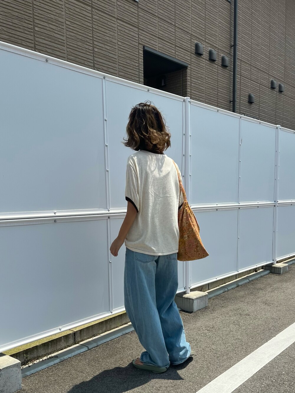 ベージュ系のTシャツ/カットソー、ブラウン系のショルダーバッグ、ブルー系のデニムパンツを着用したレディースの夏コーディネートの4枚目の写真