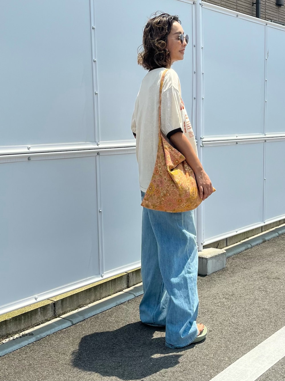 ベージュ系のTシャツ/カットソー、ブラウン系のショルダーバッグ、ブルー系のデニムパンツを着用したレディースの夏コーディネートの2枚目の写真