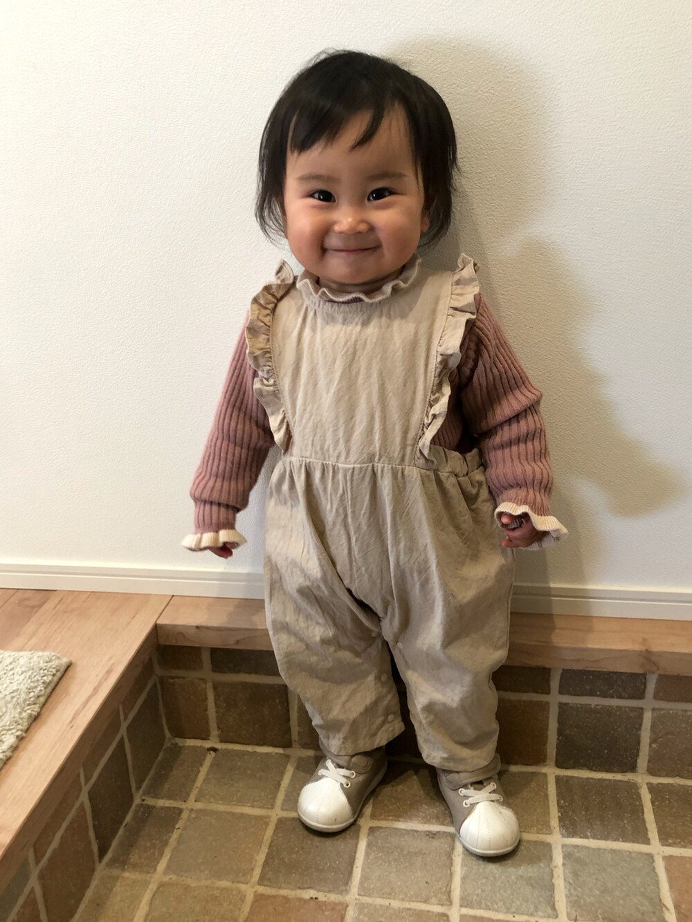 ベージュ系のサロペット/オーバーオール、ピンク系のニット/セーター、ベージュ系のスニーカーを着用したキッズの冬コーディネートの2枚目の写真