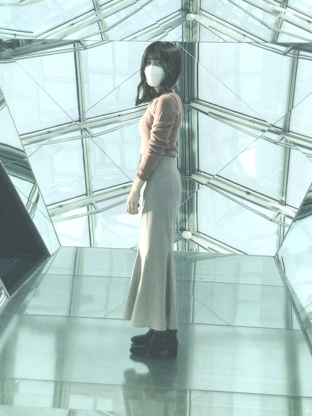 ピンク系のトップス、ブルー系のスカート、ブラック系のブーツを着用したレディースの春コーディネートの2枚目の写真