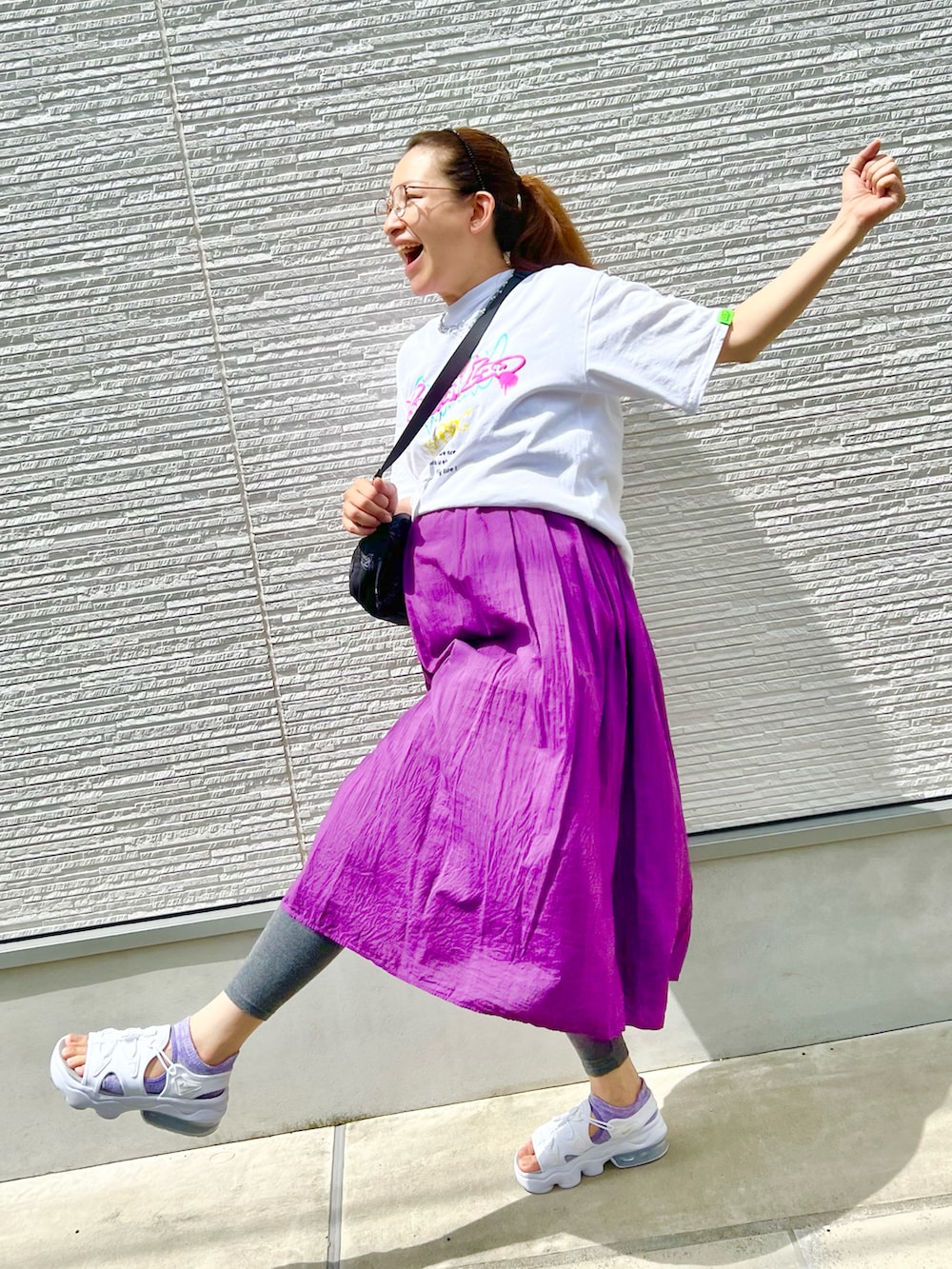 パープル系のワンピース、ホワイト系のTシャツ/カットソー、ブラック系のショルダーバッグを着用したレディースの夏コーディネートの2枚目の写真