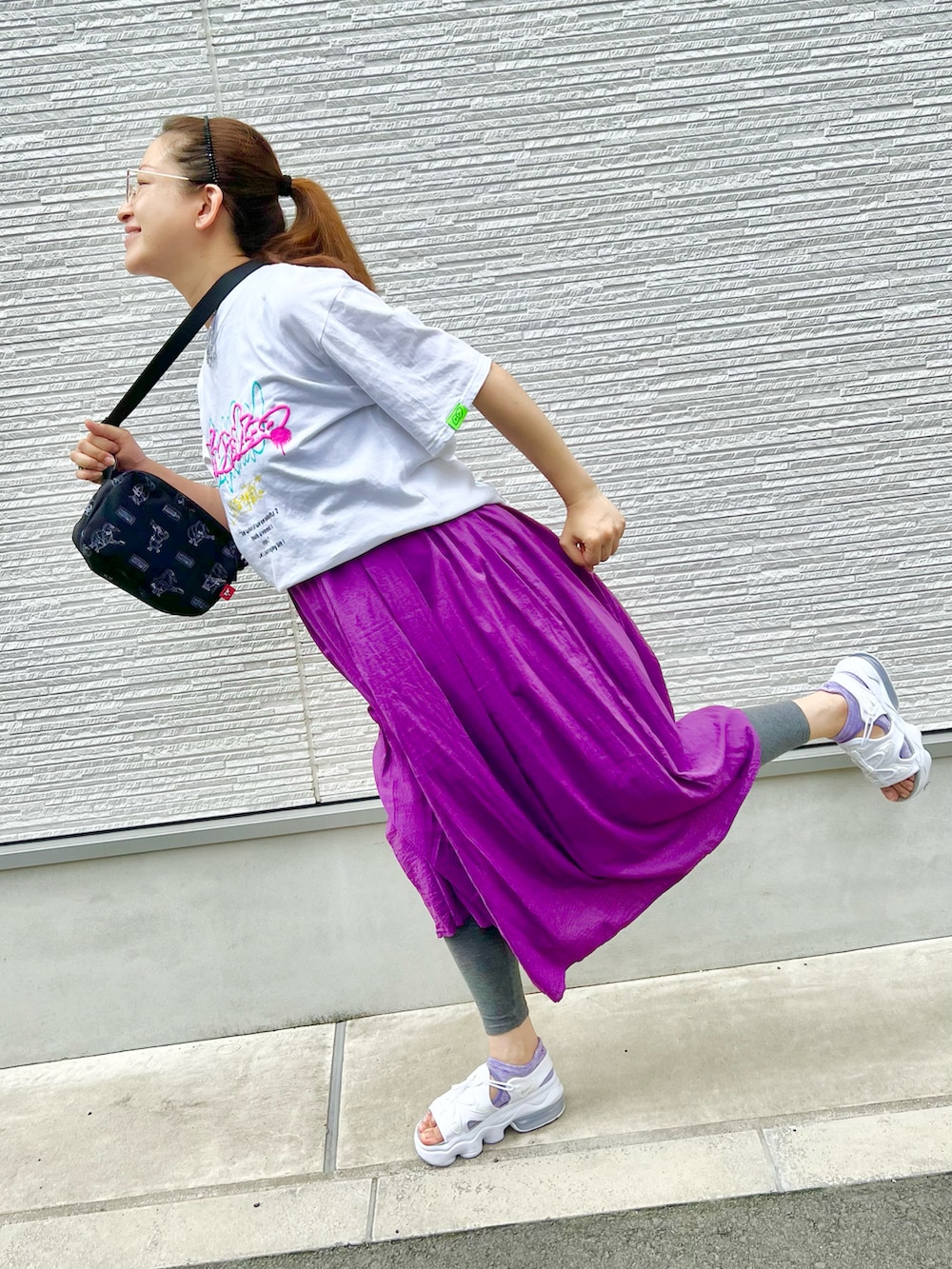 パープル系のワンピース、ホワイト系のTシャツ/カットソー、ブラック系のショルダーバッグを着用したレディースの夏コーディネートの3枚目の写真