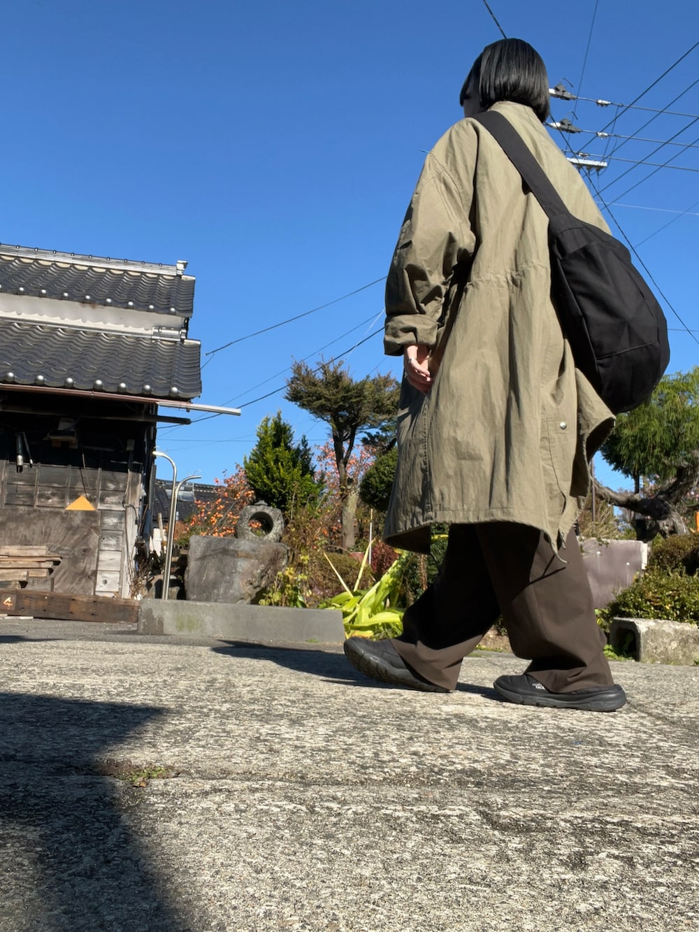 グリーン系のモッズコート、ブラック系のブーツ、ブラック系のショルダーバッグを着用したレディースの秋コーディネートの3枚目の写真