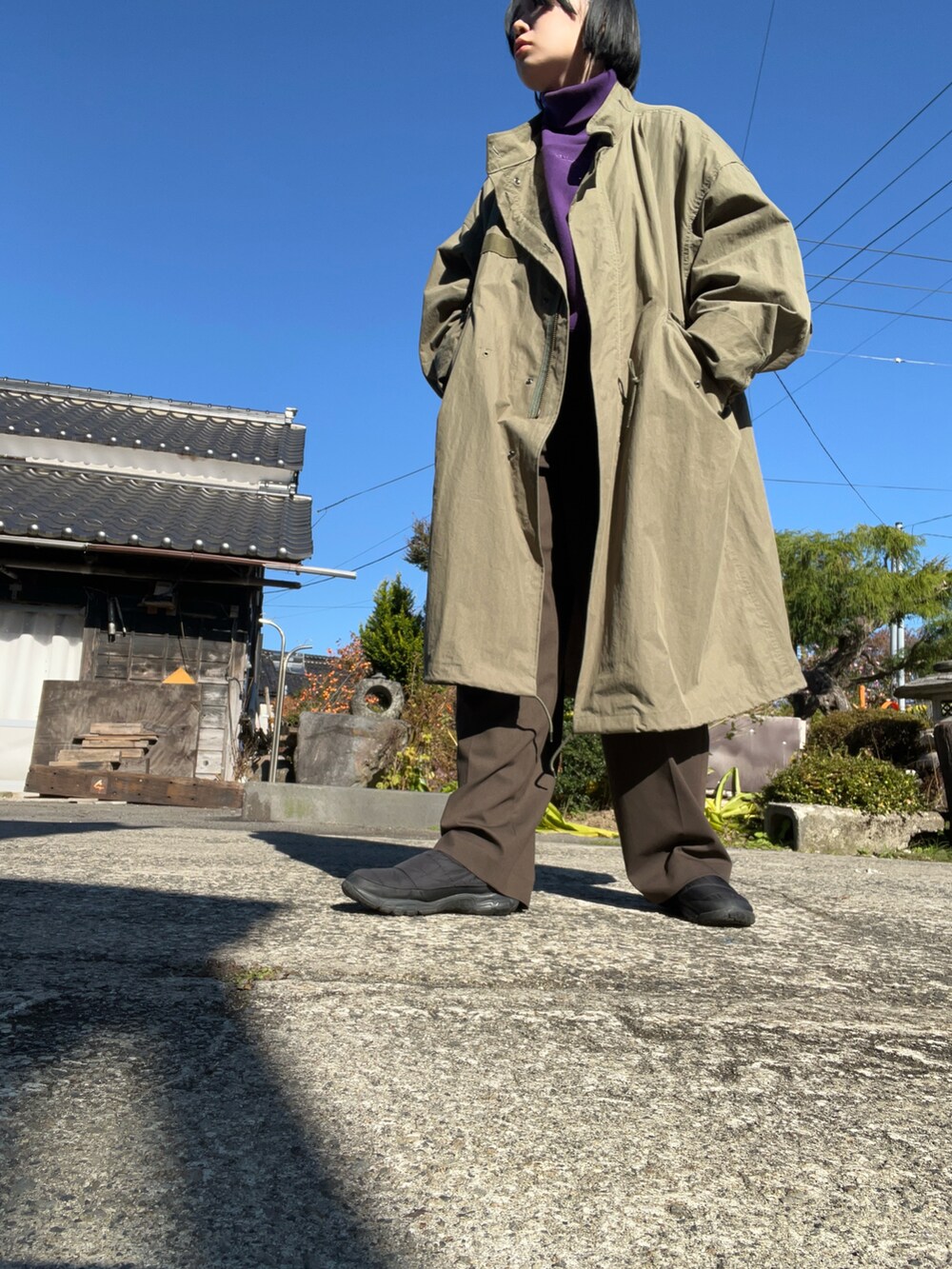 グリーン系のモッズコート、ブラック系のブーツ、ブラック系のショルダーバッグを着用したレディースの秋コーディネートの2枚目の写真