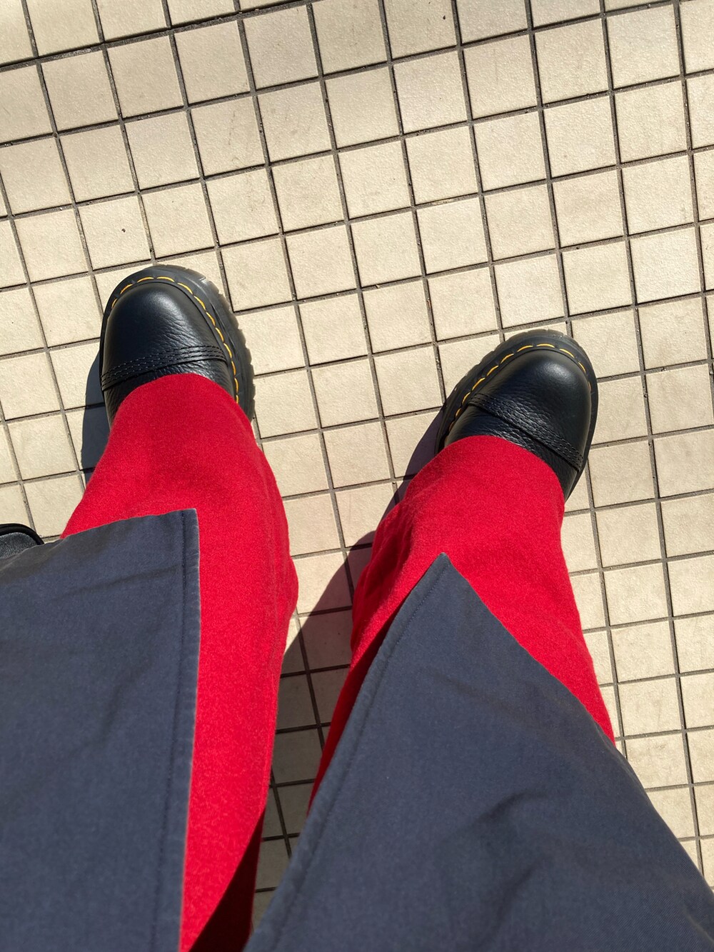 ブルー系のトレンチコート、レッド系のその他パンツ、ブラック系のブーツを着用したレディースの冬コーディネートの2枚目の写真