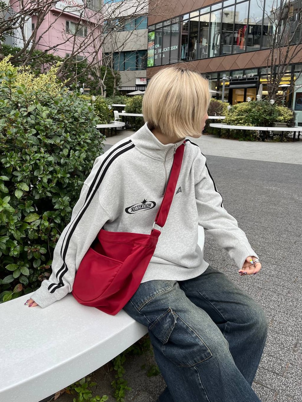 グレー系のスウェット、ブルー系のデニムパンツ、レッド系のショルダーバッグを着用したレディースの冬コーディネートの2枚目の写真