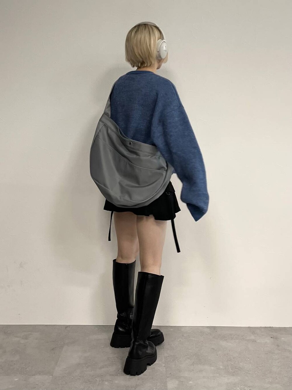 ブラック系のブーツ、ブラック系のスカート、ブルー系のニット/セーターを着用したレディースの冬コーディネートの2枚目の写真