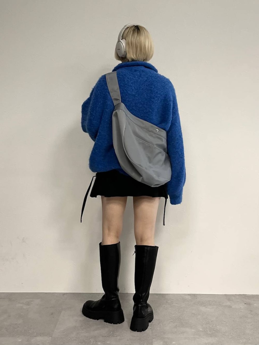 ブラック系のブーツ、ブラック系のスカート、ブルー系のニット/セーターを着用したレディースの秋コーディネートの3枚目の写真