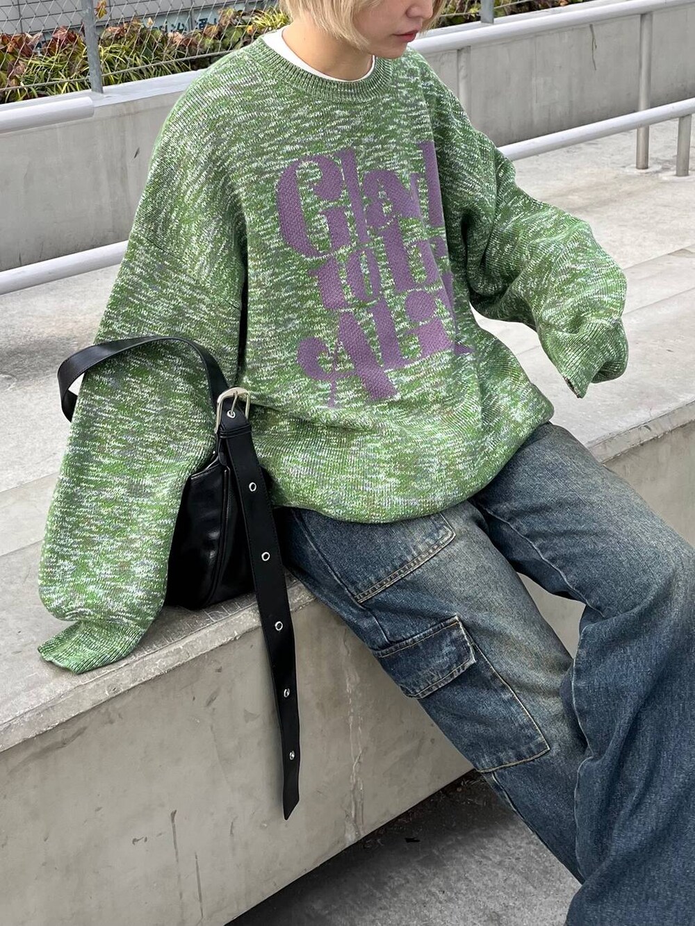 グリーン系のニット/セーター、ブラック系のショルダーバッグ、ブルー系のデニムパンツを着用したレディースの冬コーディネートの2枚目の写真