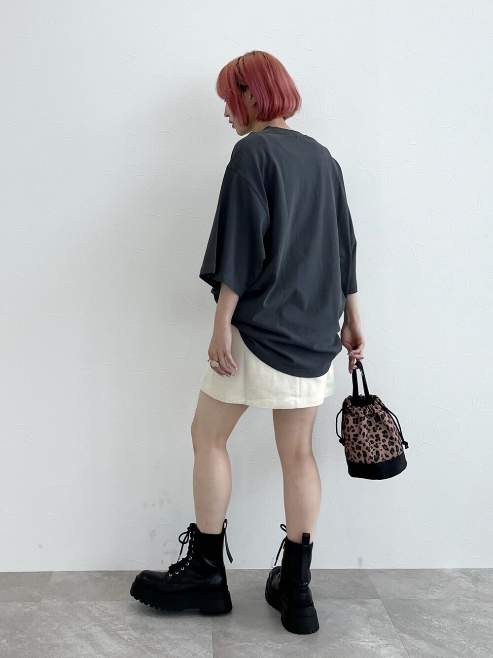 グレー系のTシャツ/カットソー、ホワイト系のスカート、ブラック系のブーツを着用したレディースの夏コーディネートの2枚目の写真