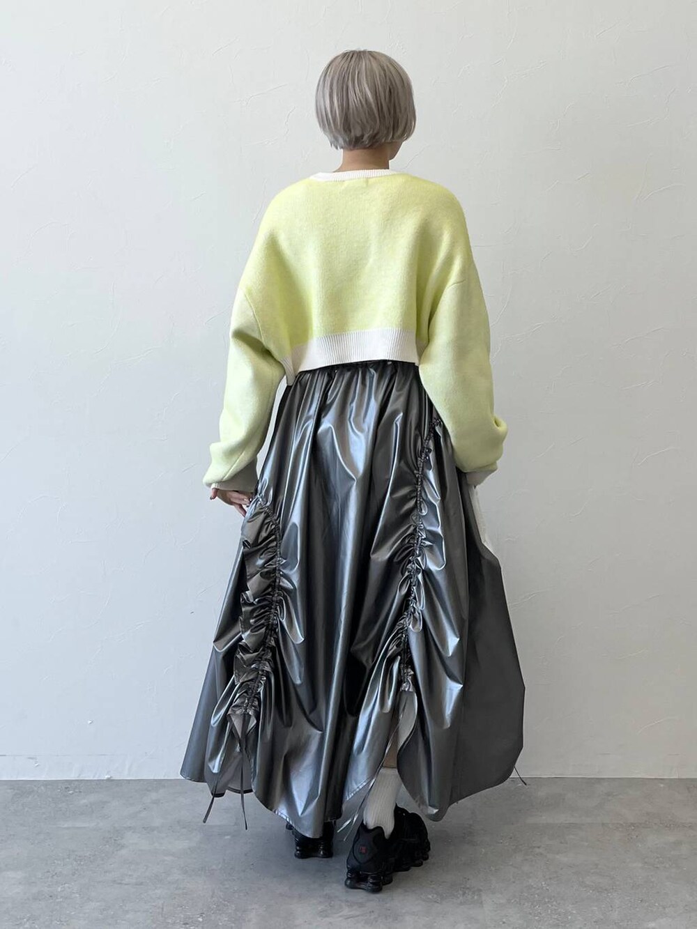 ホワイト系のニット/セーター、ホワイト系のハンドバッグ、シルバー系のスカートを着用したレディースの秋コーディネートの3枚目の写真