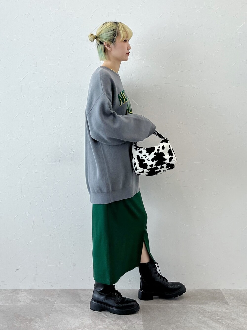 グレー系のニット/セーター、ブラック系のハンドバッグ、グリーン系のスカートを着用したレディースの秋コーディネートの2枚目の写真