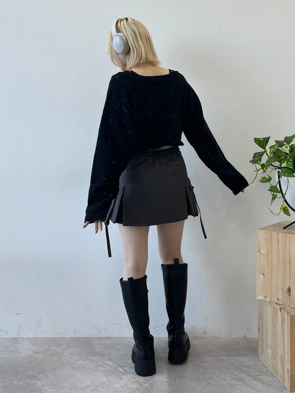 ブラック系のブーツ、グレー系のスカート、ブラック系のニット/セーターを着用したレディースの秋コーディネートの2枚目の写真