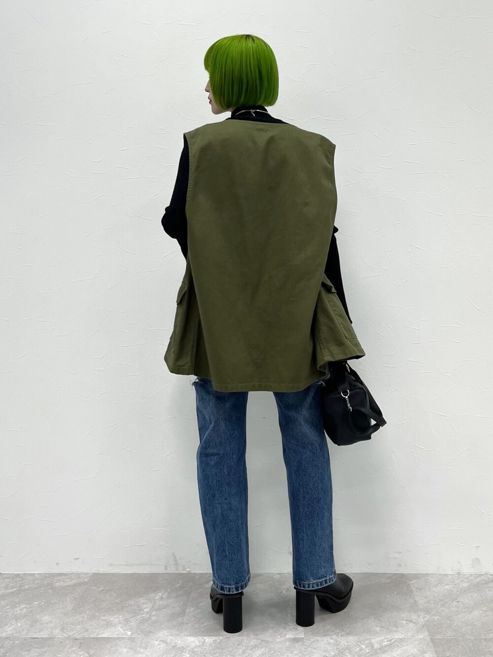 グリーン系のベスト、ブラック系のニット/セーター、ブラック系のバッグを着用したレディースの夏コーディネートの3枚目の写真