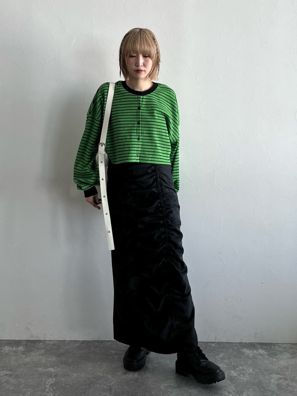 グリーン系のカーディガン/ボレロ、ブラック系のスカート、ホワイト系のショルダーバッグを着用したレディースの春コーディネートの2枚目の写真