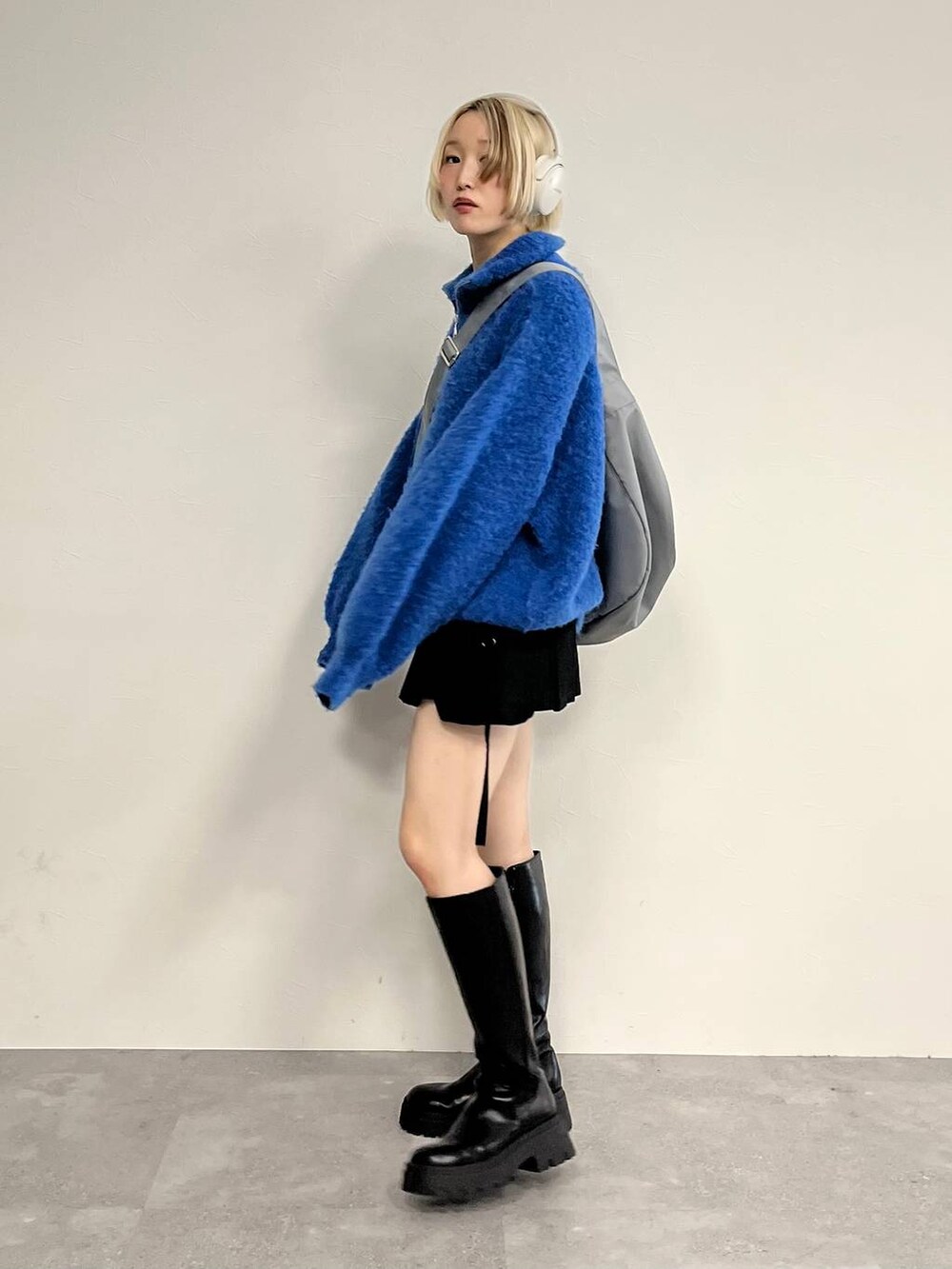 ブラック系のブーツ、ブラック系のスカート、ブルー系のニット/セーターを着用したレディースの秋コーディネートの2枚目の写真