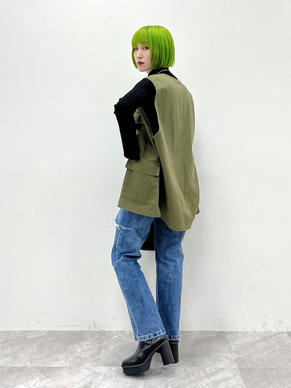 グリーン系のベスト、ブラック系のニット/セーター、ブラック系のバッグを着用したレディースの夏コーディネートの2枚目の写真